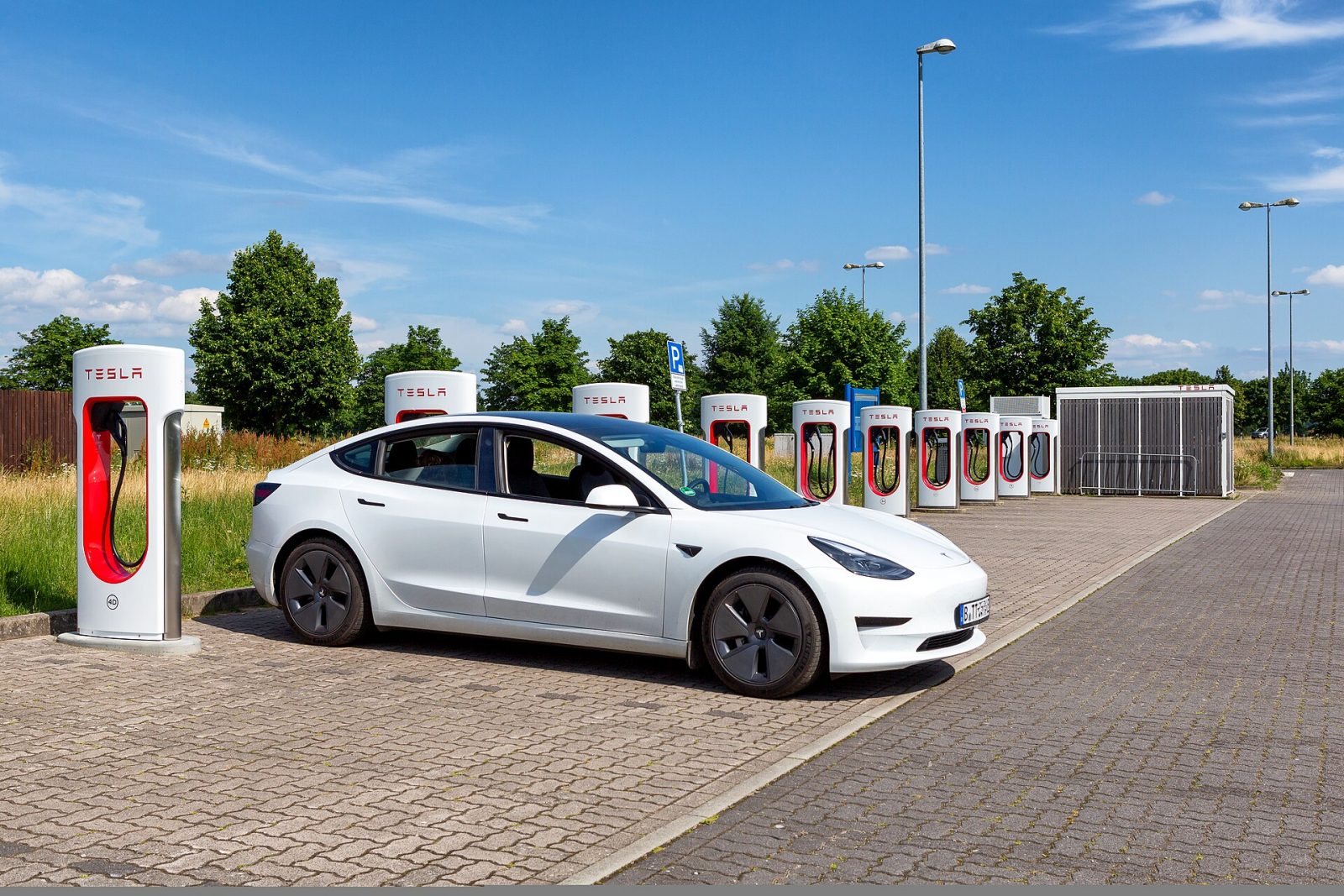 テスラのスーパーチャージャー。駐車場に充電器が1列に並び、1台が充電している
